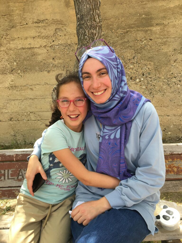 pexels-photo-13975417-13975417 A heartwarming image of a smiling woman in a hijab and a child embracing outdoors.